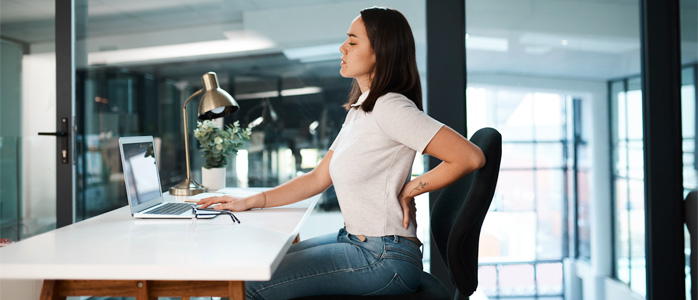 a woman at a desk with back pain